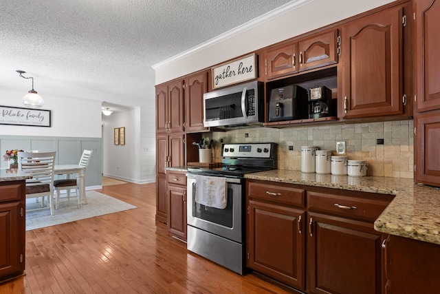 kitchen featuring light stone counters, a textured ceiling, light wood-type flooring, appliances with stainless steel finishes, and pendant lighting