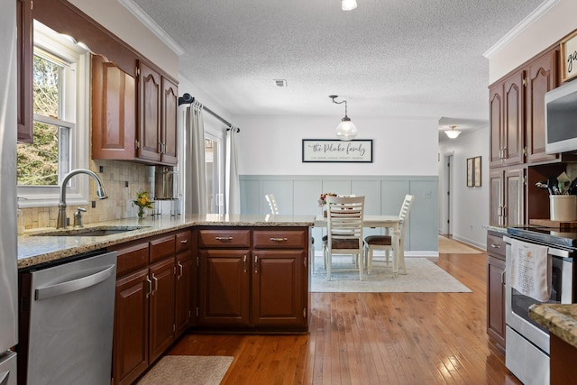 kitchen featuring sink, a textured ceiling, ornamental molding, dark hardwood / wood-style flooring, and stainless steel appliances