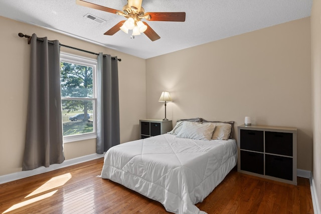 bedroom with hardwood / wood-style flooring, a textured ceiling, and ceiling fan