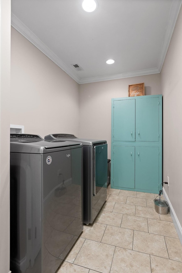 washroom featuring cabinets, crown molding, light tile patterned floors, and washer and clothes dryer