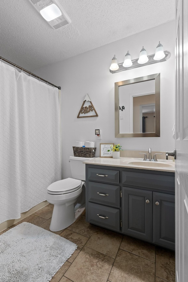 bathroom with vanity, toilet, tile patterned flooring, and a textured ceiling