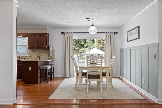 dining space featuring ornamental molding, dark hardwood / wood-style floors, sink, and a textured ceiling