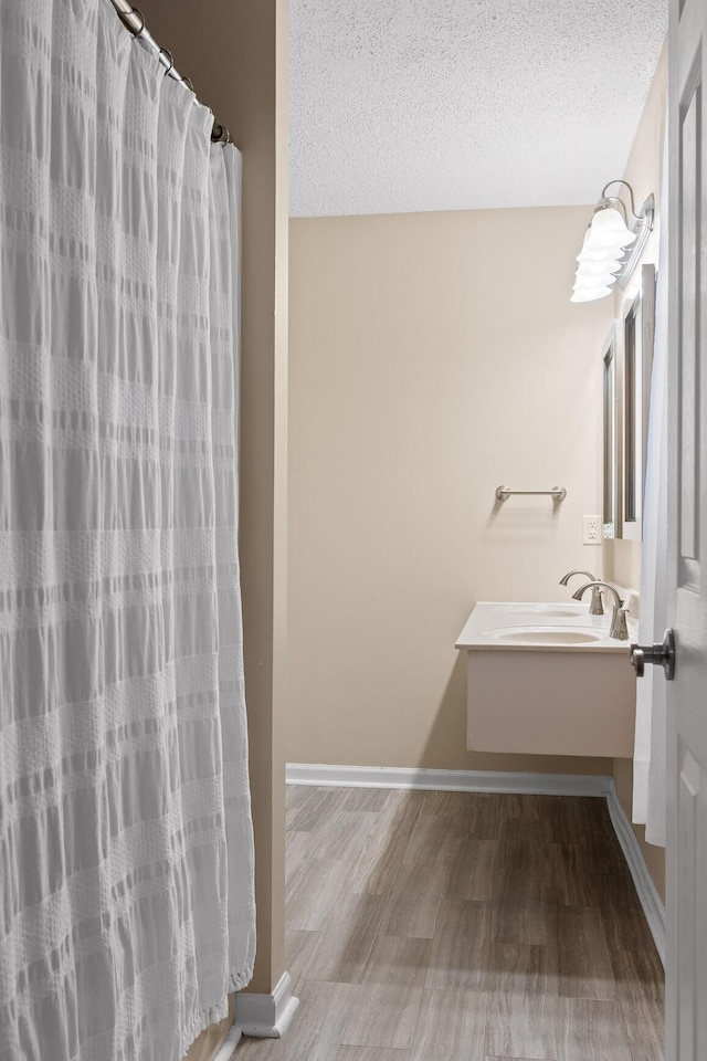 bathroom featuring vanity, hardwood / wood-style flooring, a textured ceiling, and walk in shower