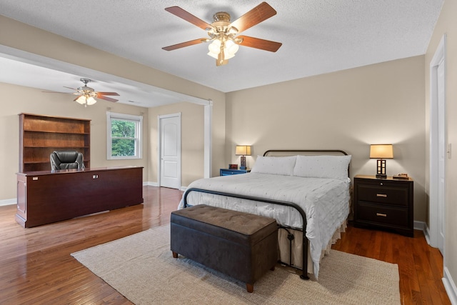 bedroom with dark hardwood / wood-style flooring, a textured ceiling, and ceiling fan