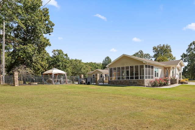 back of property featuring a yard, a gazebo, and a sunroom