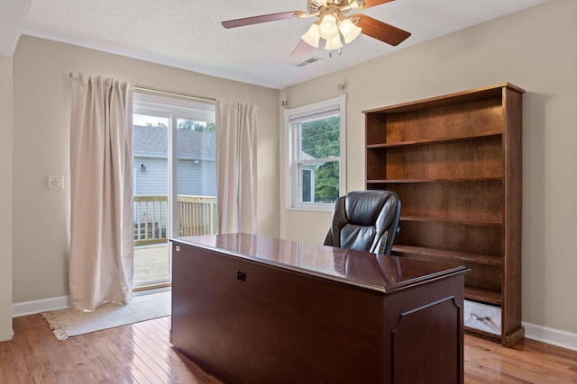 home office with ceiling fan, light hardwood / wood-style flooring, and a textured ceiling