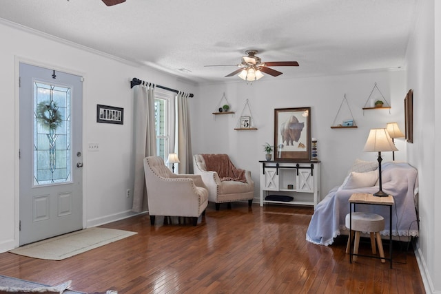 interior space with ceiling fan, ornamental molding, a textured ceiling, and dark hardwood / wood-style flooring