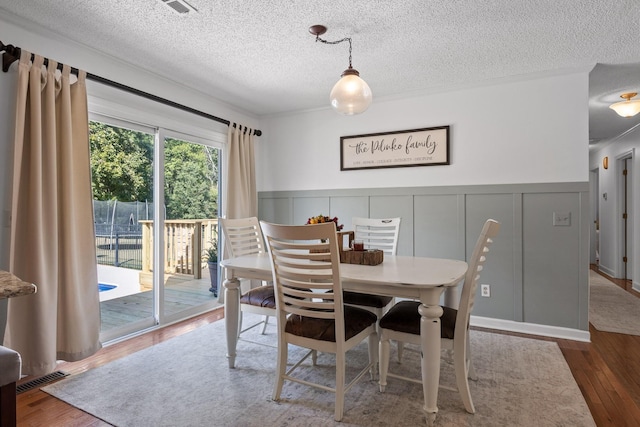 dining area featuring crown molding, hardwood / wood-style floors, and a textured ceiling