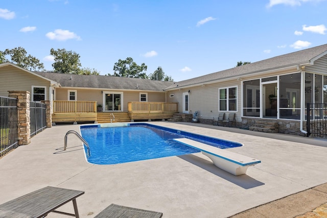 view of pool with a patio, a sunroom, a diving board, and a deck