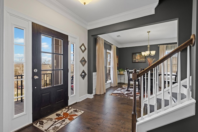 foyer entrance featuring crown molding, dark wood-type flooring, and an inviting chandelier