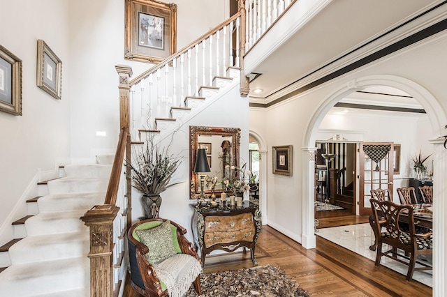 staircase featuring hardwood / wood-style floors, crown molding, and a high ceiling