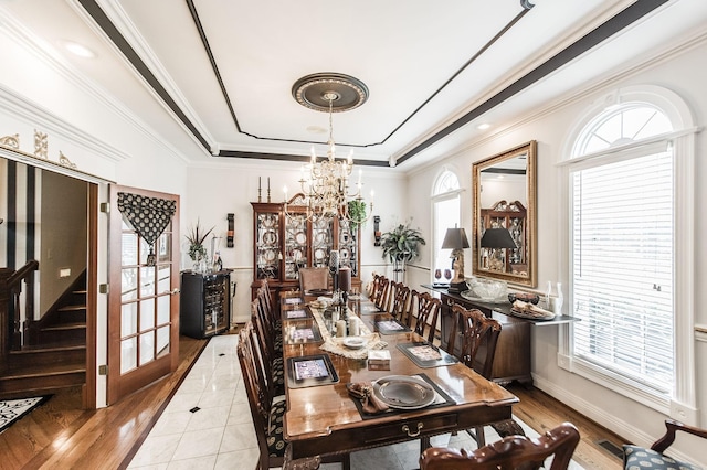 tiled dining room with a raised ceiling, crown molding, and an inviting chandelier