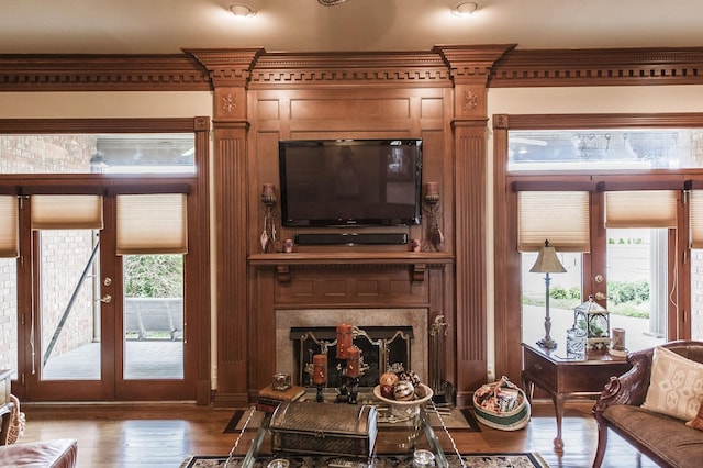 living room with a premium fireplace, wood-type flooring, a healthy amount of sunlight, and ornamental molding