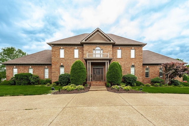 view of front facade featuring a balcony and a front lawn