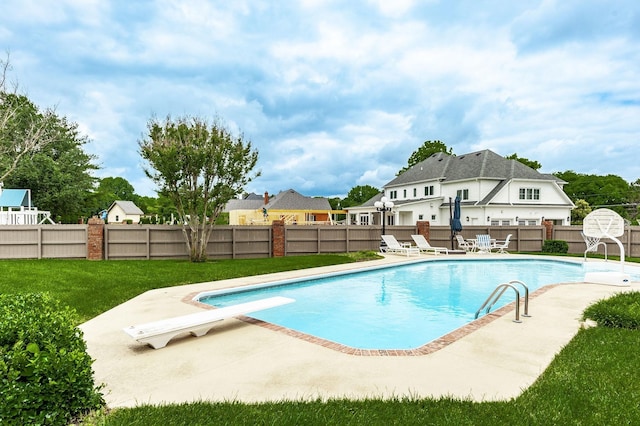 view of pool with a patio, a yard, and a diving board