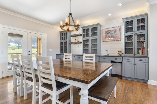 interior space with an inviting chandelier, ornamental molding, french doors, and light wood-type flooring