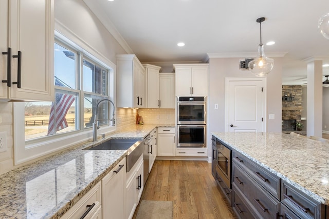 kitchen with white cabinetry, appliances with stainless steel finishes, light stone countertops, and hanging light fixtures