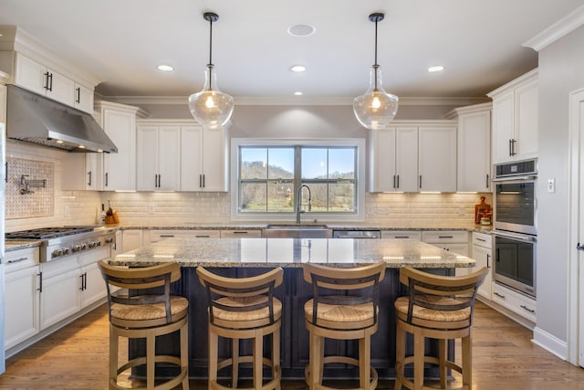 kitchen with sink, white cabinetry, decorative light fixtures, a kitchen island, and stainless steel appliances