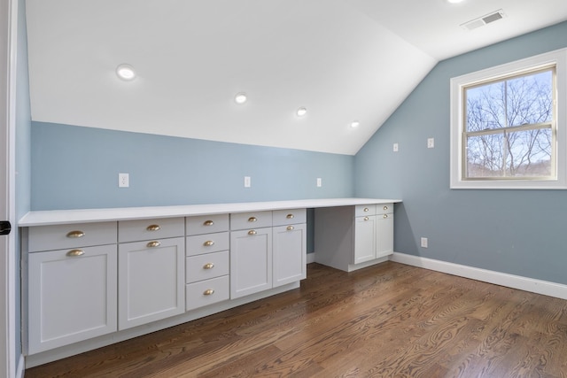 interior space with dark hardwood / wood-style flooring, vaulted ceiling, and white cabinets