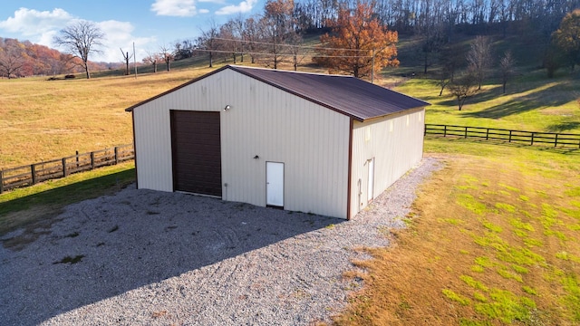 view of outbuilding with a rural view, a garage, and a lawn