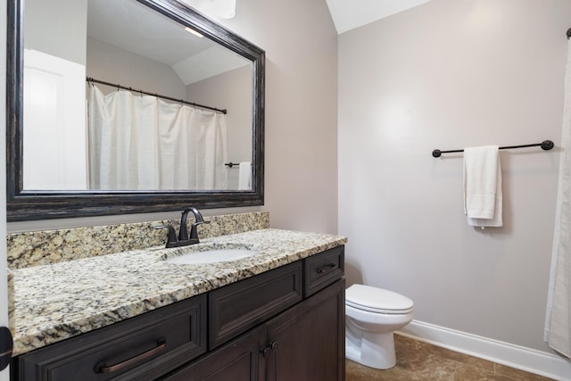 bathroom featuring vanity, toilet, and vaulted ceiling