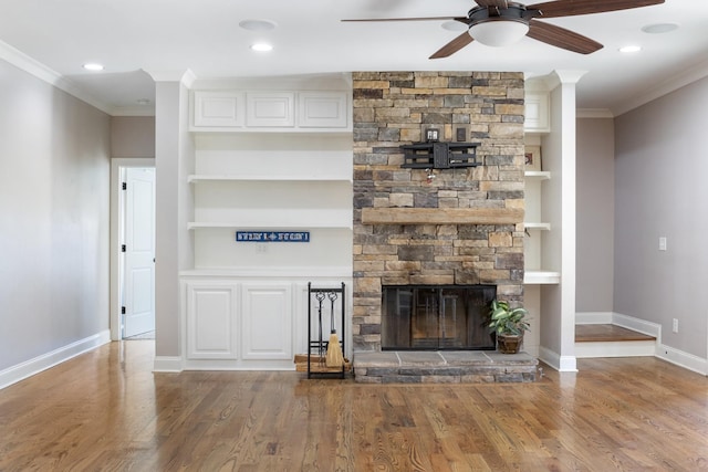 unfurnished living room with built in shelves, a fireplace, ornamental molding, and hardwood / wood-style flooring