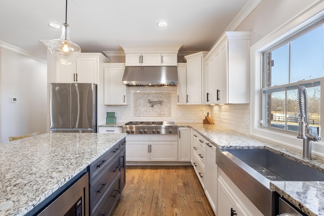 kitchen featuring sink, appliances with stainless steel finishes, white cabinetry, light stone countertops, and decorative light fixtures