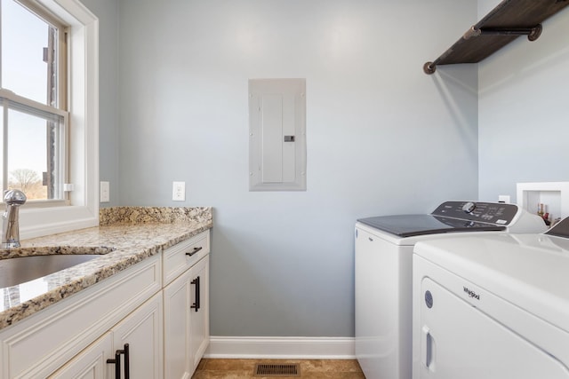 clothes washing area featuring cabinets, washing machine and dryer, sink, and electric panel