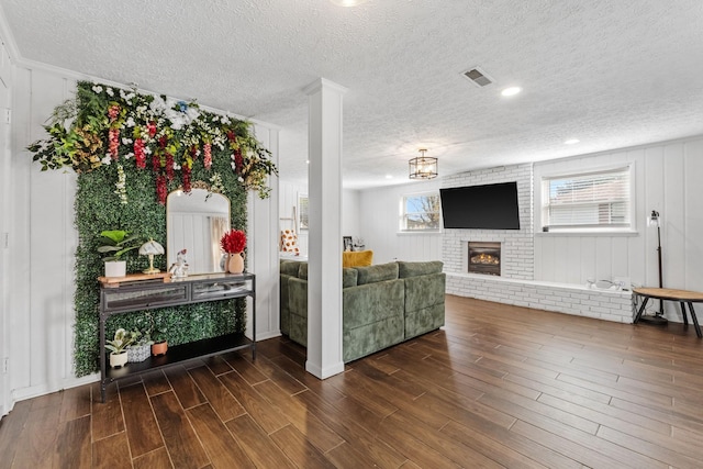 living room featuring a brick fireplace, a wealth of natural light, and a textured ceiling