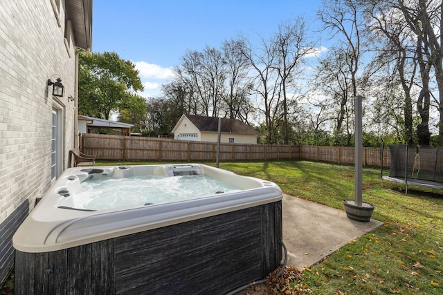 view of yard featuring a trampoline and a hot tub