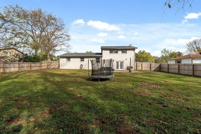 rear view of house with a trampoline and a lawn