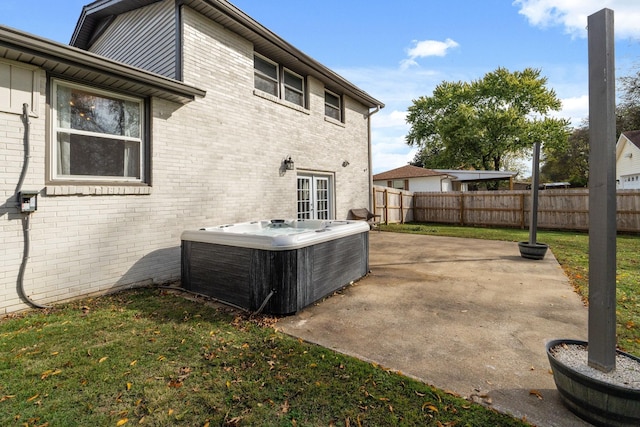 rear view of house with cooling unit, a hot tub, a patio area, and a lawn