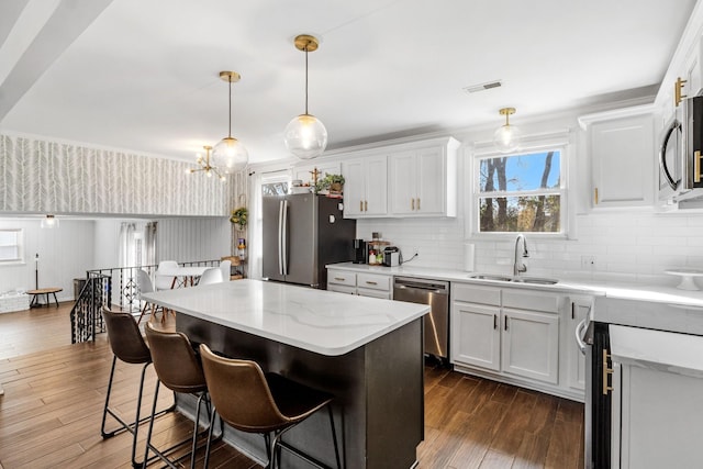 kitchen with stainless steel appliances, hanging light fixtures, sink, and white cabinets