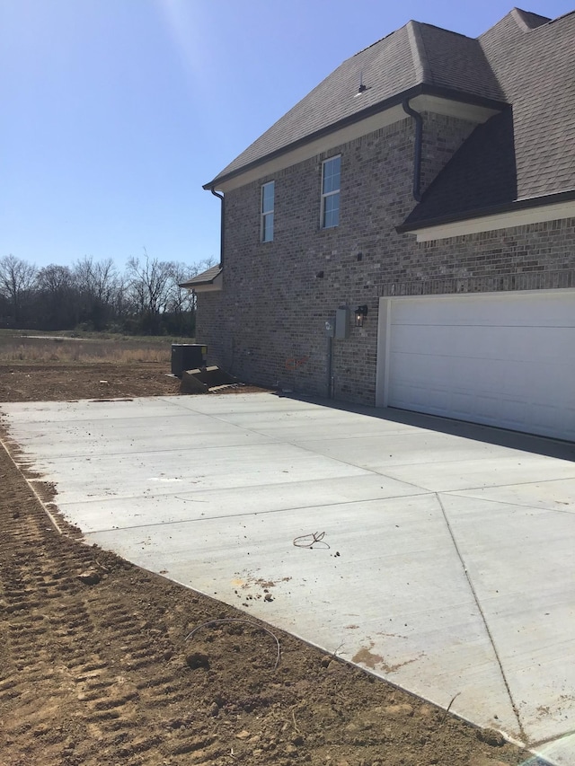 view of home's exterior with a garage, brick siding, and driveway