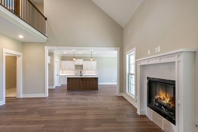 living area featuring high vaulted ceiling, baseboards, and a warm lit fireplace