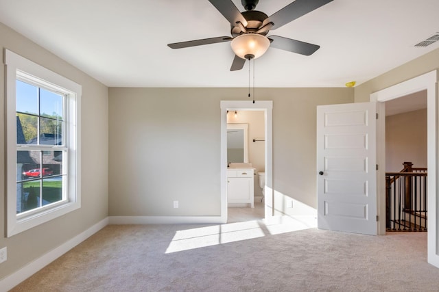 unfurnished bedroom with ensuite bath, visible vents, light colored carpet, and baseboards
