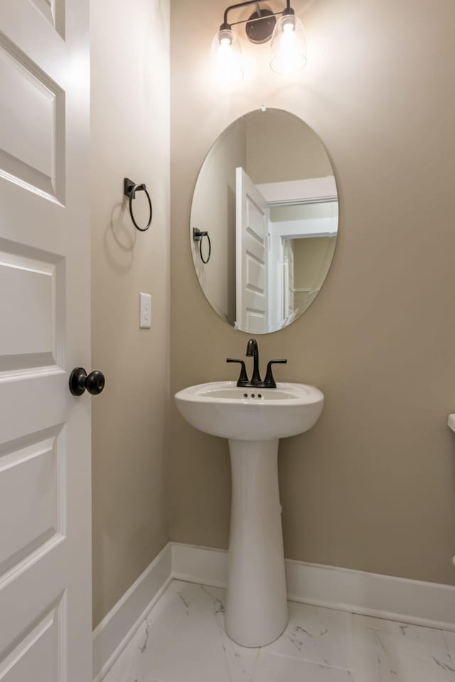 bathroom with a sink, marble finish floor, and baseboards