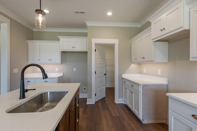kitchen featuring dark wood-style flooring, ornamental molding, light countertops, visible vents, and a sink
