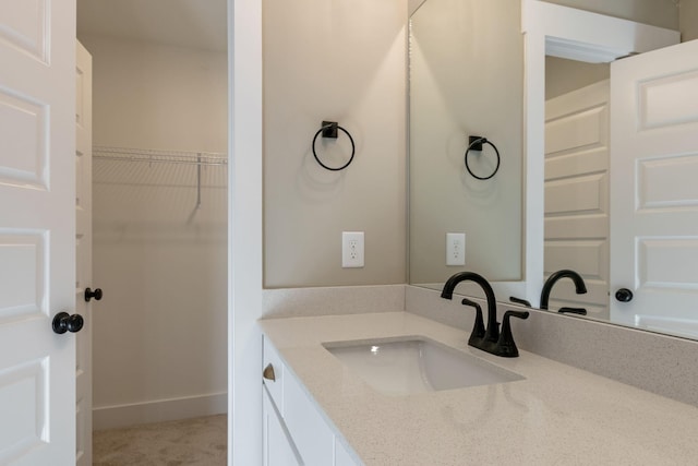 bathroom featuring vanity, baseboards, and a spacious closet