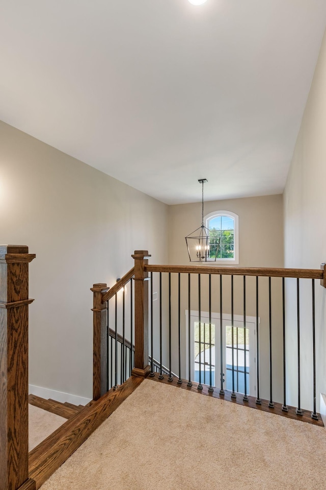 staircase with carpet floors, baseboards, and an inviting chandelier