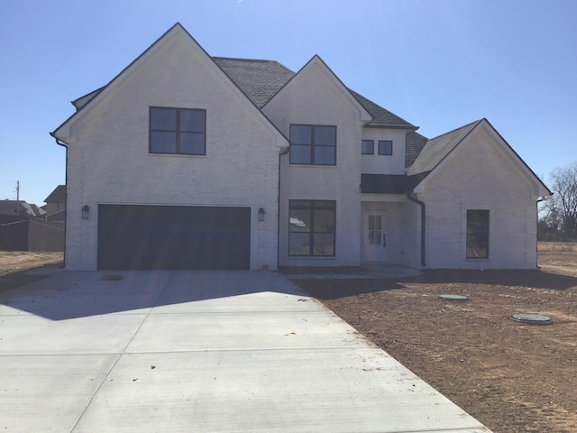 view of front of property featuring brick siding, driveway, an attached garage, and roof with shingles