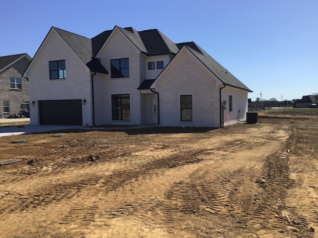 view of front of house with a garage, cooling unit, and brick siding