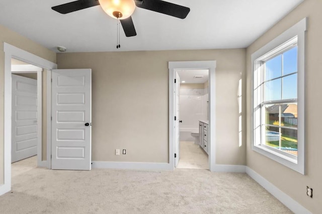 unfurnished bedroom featuring light carpet, ceiling fan, baseboards, and connected bathroom
