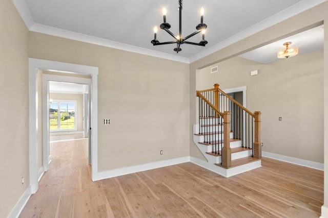 spare room featuring a chandelier, stairway, light wood-style flooring, and crown molding