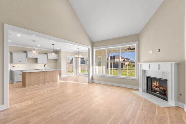 unfurnished living room with a premium fireplace, a sink, plenty of natural light, and light wood-style flooring