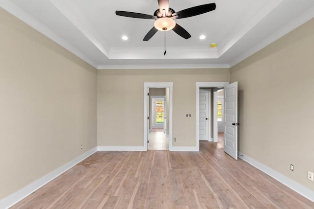 unfurnished bedroom featuring baseboards, crown molding, a tray ceiling, recessed lighting, and light wood-style flooring
