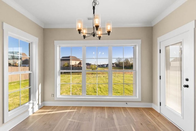 unfurnished dining area with a chandelier, a wealth of natural light, and light wood-type flooring