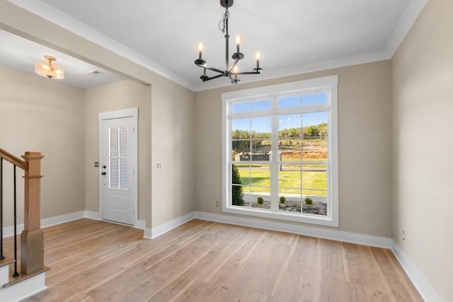 entryway with light wood finished floors, a notable chandelier, ornamental molding, and stairs