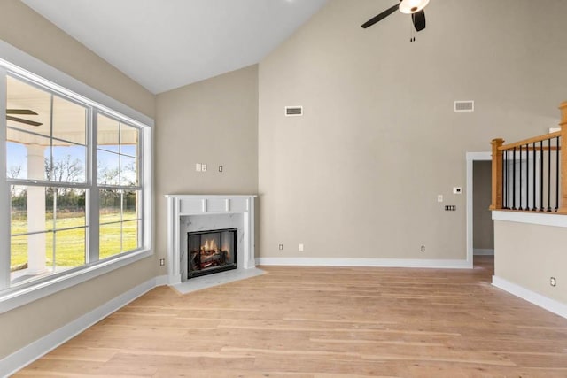 unfurnished living room featuring a premium fireplace, high vaulted ceiling, ceiling fan, and visible vents