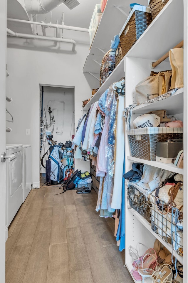 spacious closet featuring washer and dryer and light hardwood / wood-style floors